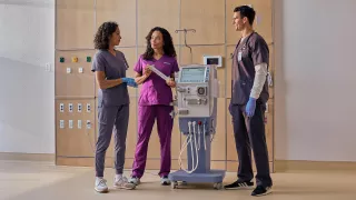 A Vantive employee demonstrates the AK 98 Dialysis Machine to two clinicians