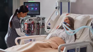 A clinician uses the PrisMax system at the patient bedside