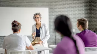 Woman in a white coat speaks to her audience