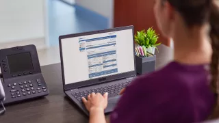 Healthcare professional views an online learning resource on a laptop at her desk