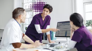 Nurse pointing at screen with purple dots in background