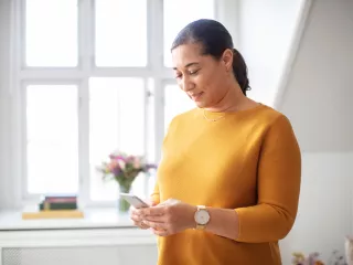 A woman looks at her mobile device in a well-lit living room