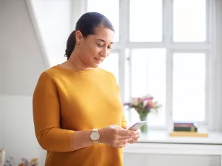 Patient standing with mobile device in their home