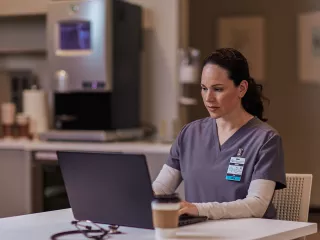 Healthcare professional sitting at table on laptop