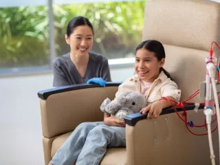 Young patient receives HD therapy sitting in a chair with a clinician beside her