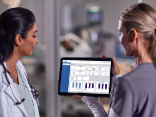 Two female healthcare professionals look at data on an tablet
