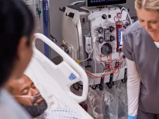 Healthcare professionals attend to a patient in front of a PrisMax System